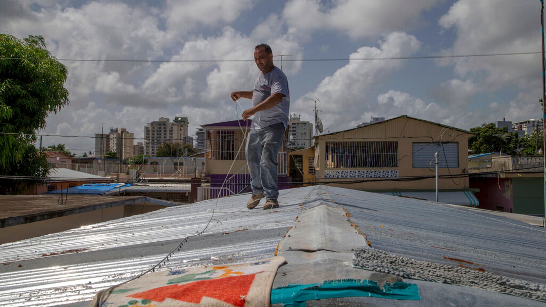 Jorge Ortiz works to tie down his roof as he prepares for the arrival of Tropical Storm Dorian, in the Martín Peña neighborhood of San Juan, Puerto Rico. (AP Photo/Gianfranco Gaglione)