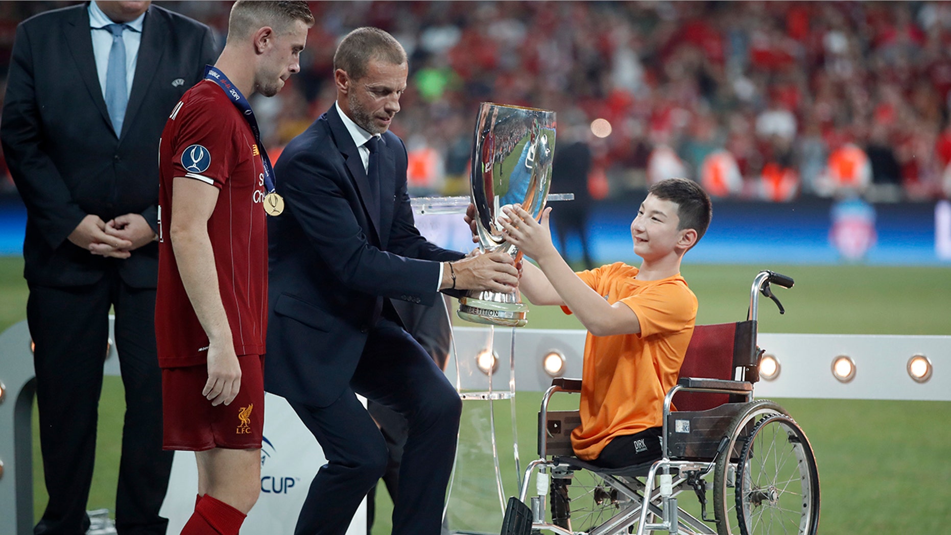 UEFA President Aleksander Ceferin and Ali Turganbekov, from Kazakhstan, right, hand the trophy to Liverpool's team captain Jordan Henderson after Liverpool won the UEFA Super Cup soccer match between Liverpool and Chelsea, in Besiktas Park, in Istanbul, Thursday, Aug. 15, 2019. Liverpool won 5-4 in a penalty shootout after the game ended tied 2-2. (AP Photo/Thanassis Stavrakis)