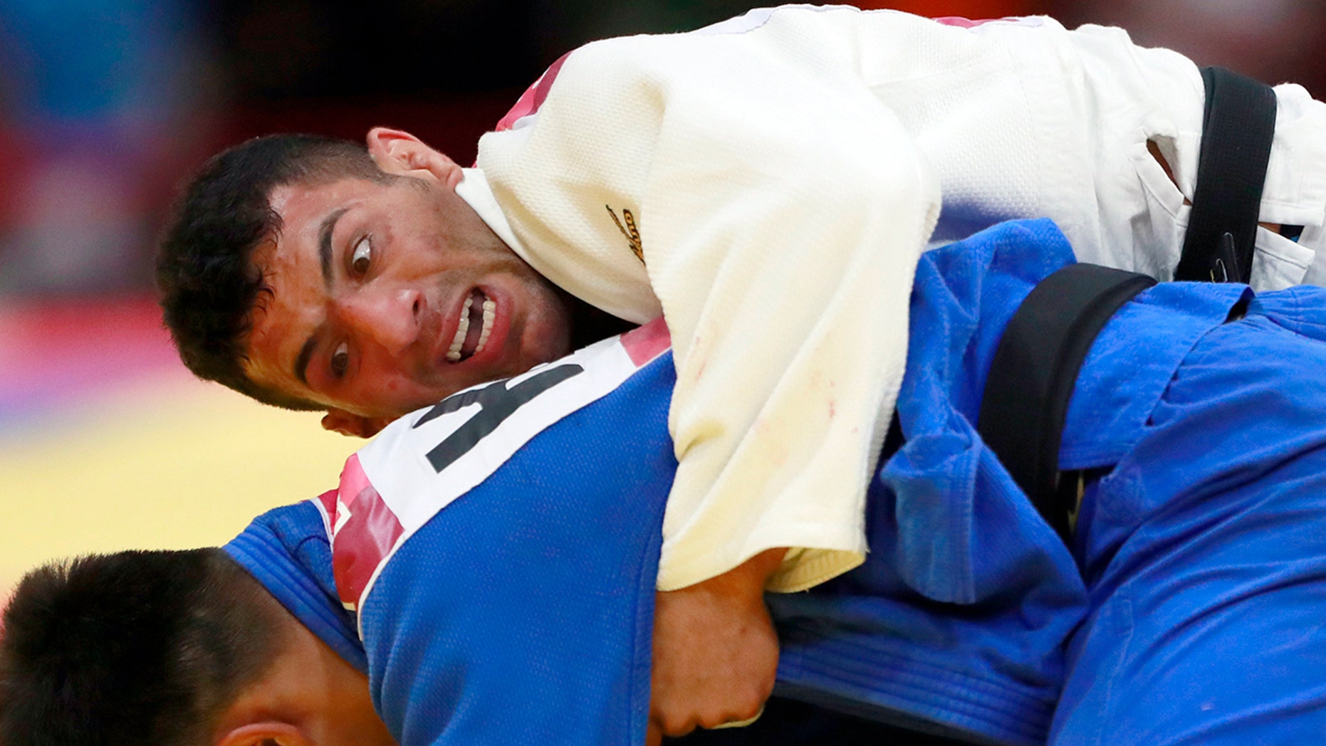 FILE - In this Thursday, Aug. 30, 2018 file photo, Saeid Mollaei of Iran, top, competes against Didar Khamza of Kazakhstan during their men's - 81kg final judo match at the18th Asian Games in Jakarta, Indonesia. Judo world champion Iran has been banned from international judo competitions for refusing to let its athletes fight Israeli opponents. The International Judo Federation has imposed an indefinite ban on Iran’s team until it promises to end a long-running boycott of Israel. (AP Photo/Tatan Syuflana, File)