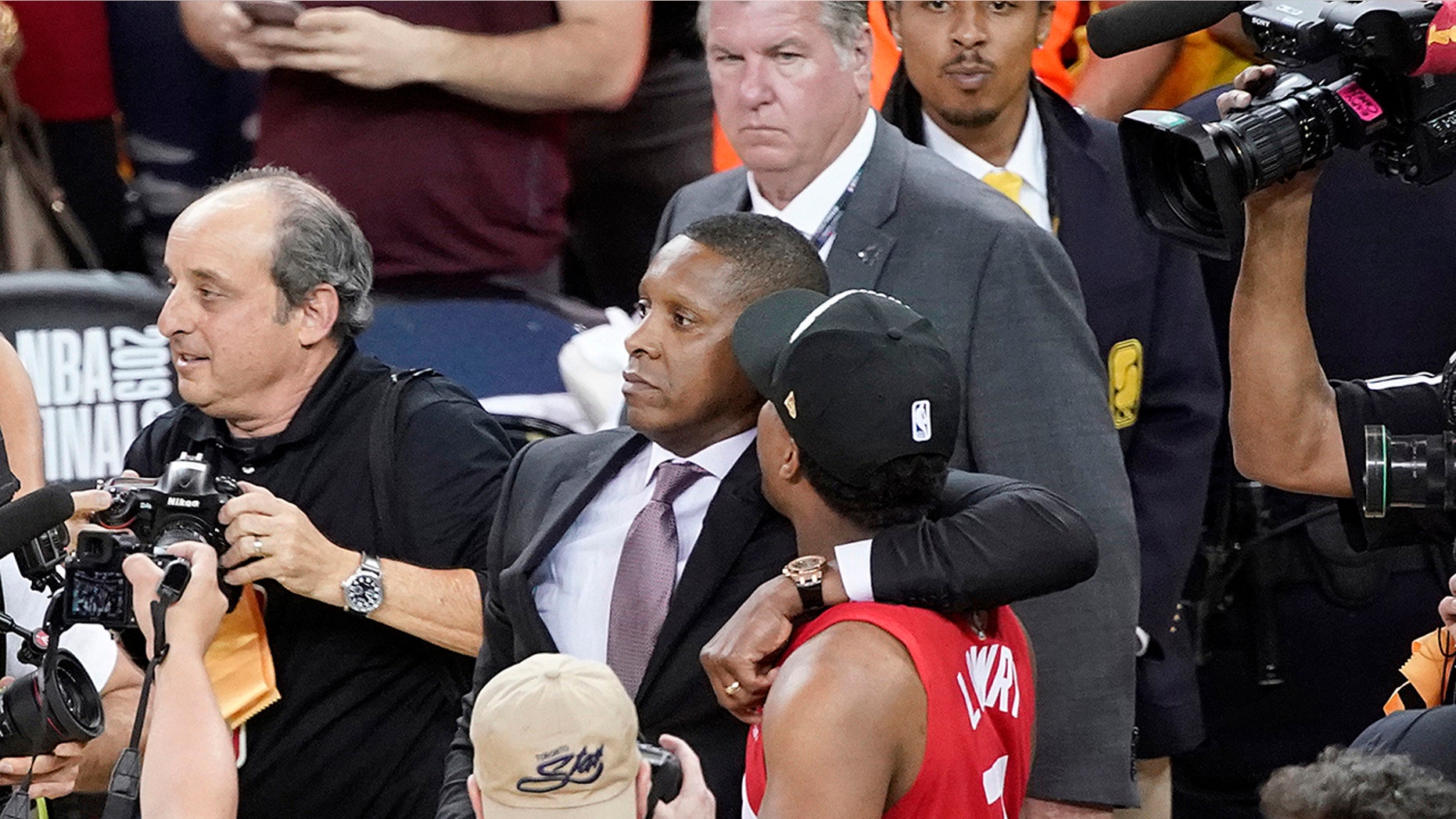 FILE - In this June 13, 2019, file photo, Toronto Raptors President Masai Ujiri, center left, walks with his arm around guard Kyle Lowry after the Raptors defeated the Golden State Warriors in basketball's NBA Finals in Oakland, Calif. On Tuesday, Oct. 22, 2019, the Alameda County District Attorney's Office announced no criminal charges will be filed against Ujiri for an incident involving Ujiri and an Alameda County sheriff's deputy after Game 6 of the finals. (AP Photo/Tony Avelar, File)