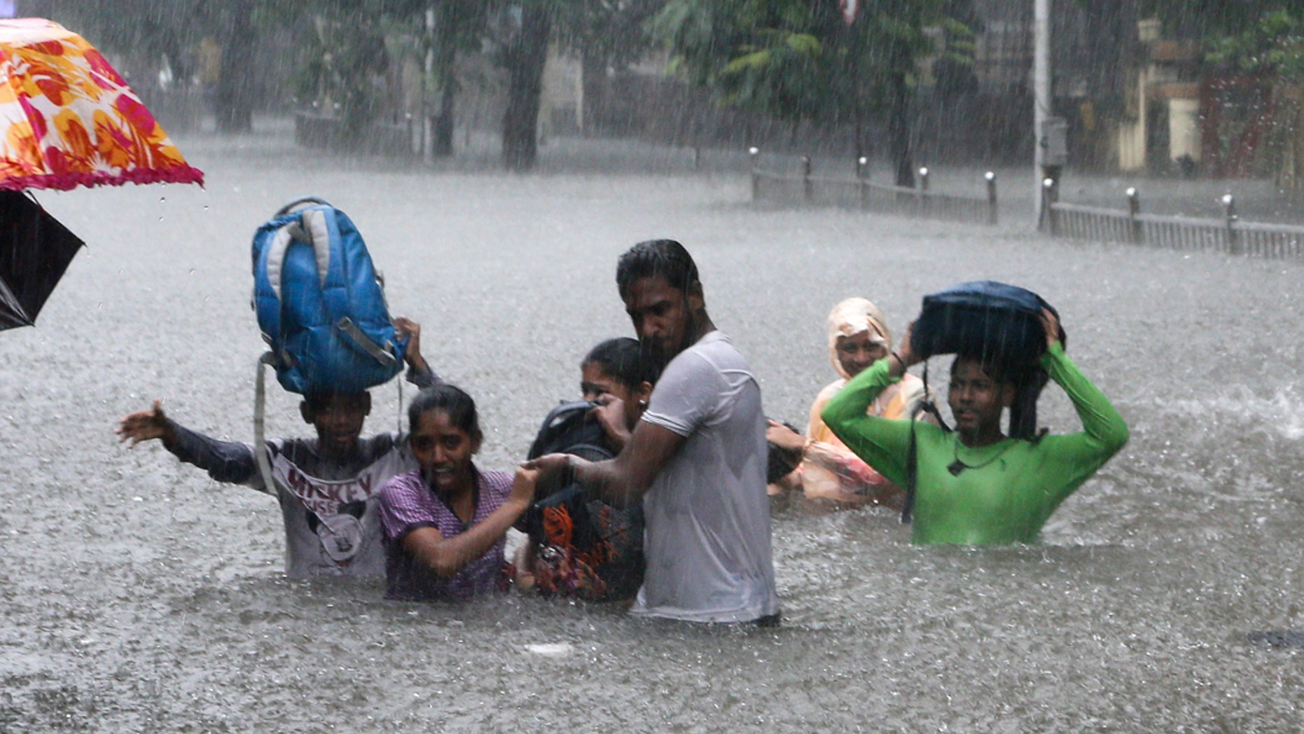 FILE - In this Sept. 4, 2019, file photo, people hold hands and navigate their way through a flooded street as it rains in Mumbai, India. The number of people threatened by climate change-triggered flooding is about three times higher than previously thought, a new study says. But it's not because of more water. It's because the land, especially in Asia and the developing world, is several feet lower than what space-based radar has calculated, according to a study in the journal Nature Communications Tuesday, Oct. 29. (AP Photo/Rajanish Kakade, File)