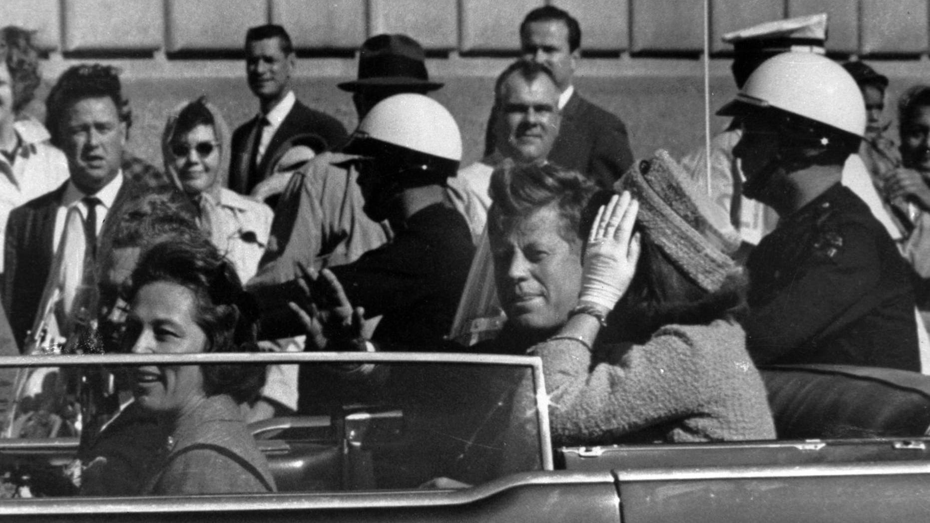 President John F. Kennedy is seen riding in motorcade approximately one minute before he was shot in Dallas, Tx., on Nov. 22, 1963. In the car riding with Kennedy are Mrs. Jacqueline Kennedy, right, Nellie Connally, left, and her husband, Gov. John Connally of Texas. (AP Photo/Jim Altgens)