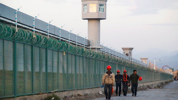 FILE PHOTO: Workers walk by the perimeter fence of what is officially known as a vocational skills education centre in Dabancheng in Xinjiang Uighur Autonomous Region, China September 4, 2018. This centre, situated between regional capital Urumqi and tourist spot Turpan, is among the largest known ones, and was still undergoing extensive construction and expansion at the time the photo was taken. Picture taken September 4, 2018. REUTERS/Thomas Peter/File Photo - RC112C876810