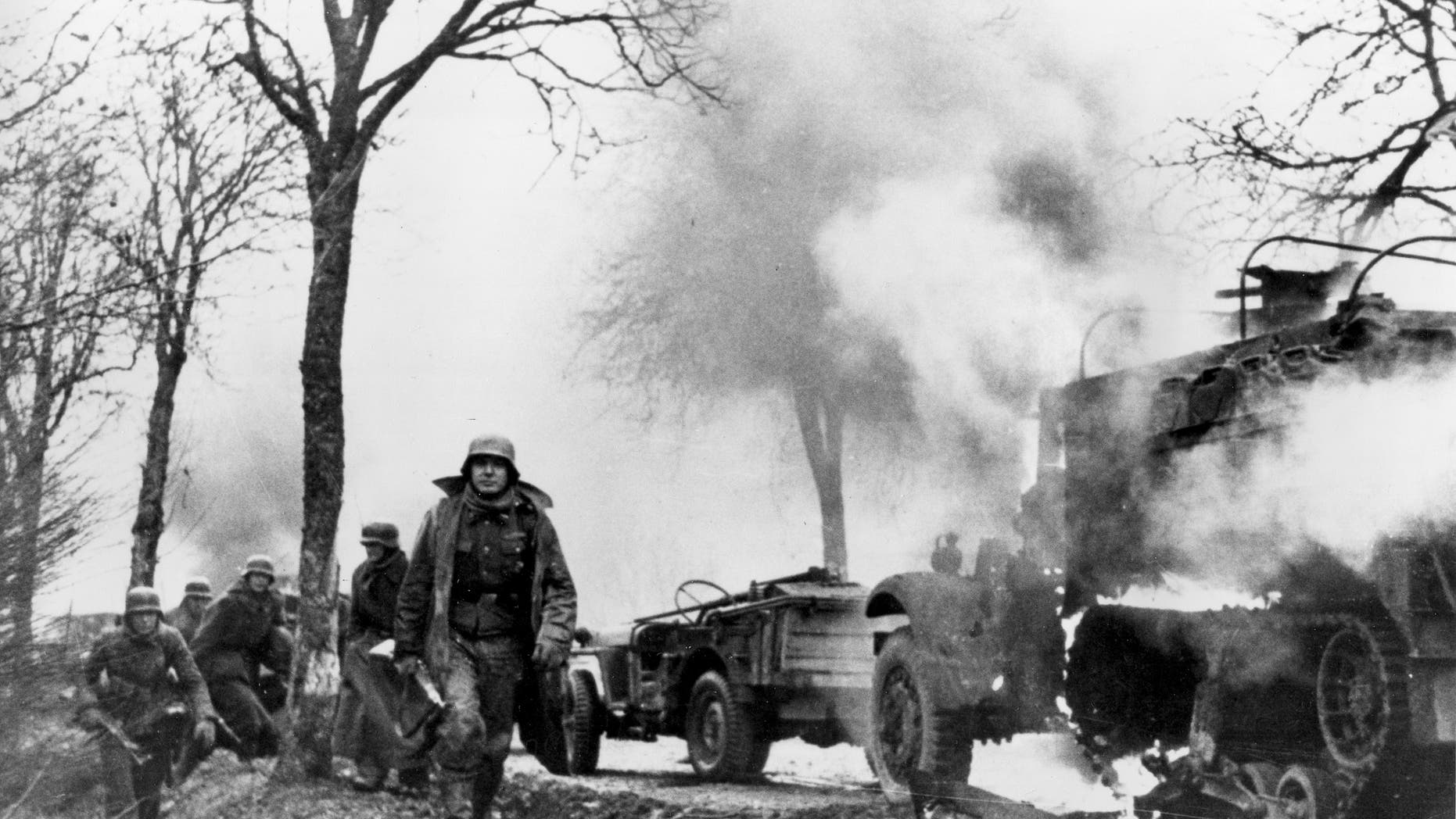 In this Dec. 1944 file photo, German infantrymen pass by burning captured American vehicles during the drive into Allied lines on the Western Front during the Battle of the Bulge.