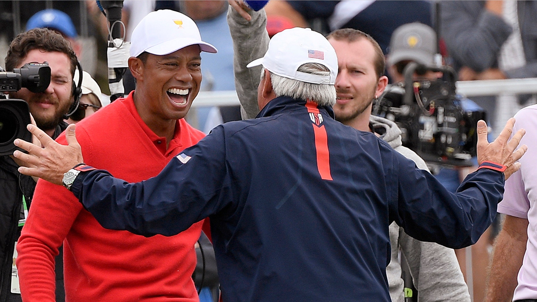 U.S. team player and captain Tiger Woods, left, celebrates with vice captain Fred Couples after Woods won his singles match during the President's Cup golf tournament at Royal Melbourne Golf Club in Melbourne, Sunday, Dec. 15, 2019. (AP Photo/Andy Brownbill)