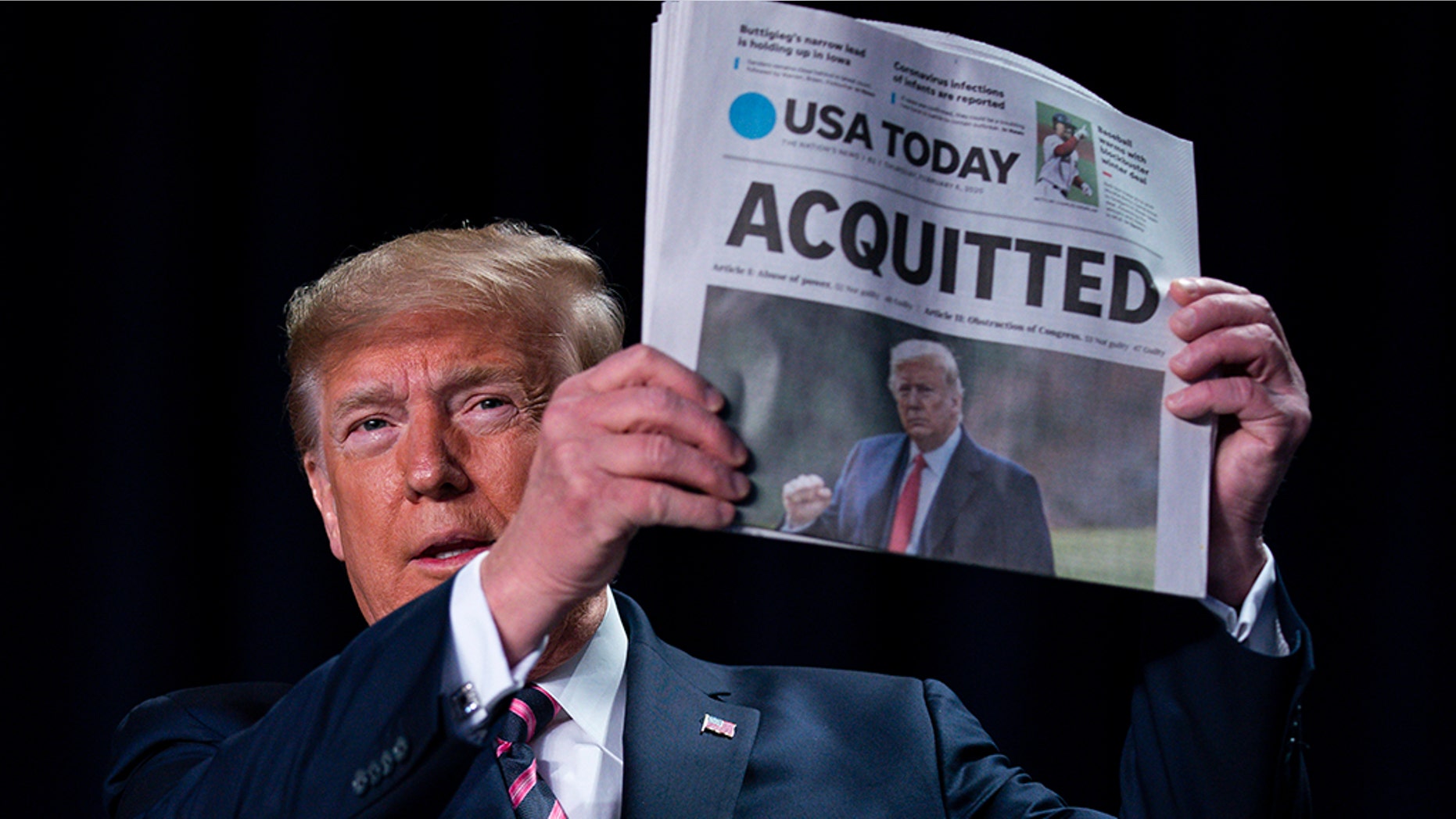 President Donald Trump holds up a newspaper with the headline that reads 