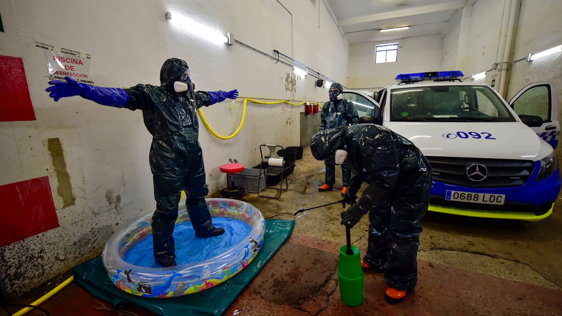 Volunteer workers of Search and Rescue (SAR) with special equipment, disinfect a volunteer while disinfecting police car at Local Police station to prevent the spread of coronavirus COVID-19, in Pamplona, northern Spain, Sunday, March 22, 2020. (AP Photo/Alvaro Barrientos)
