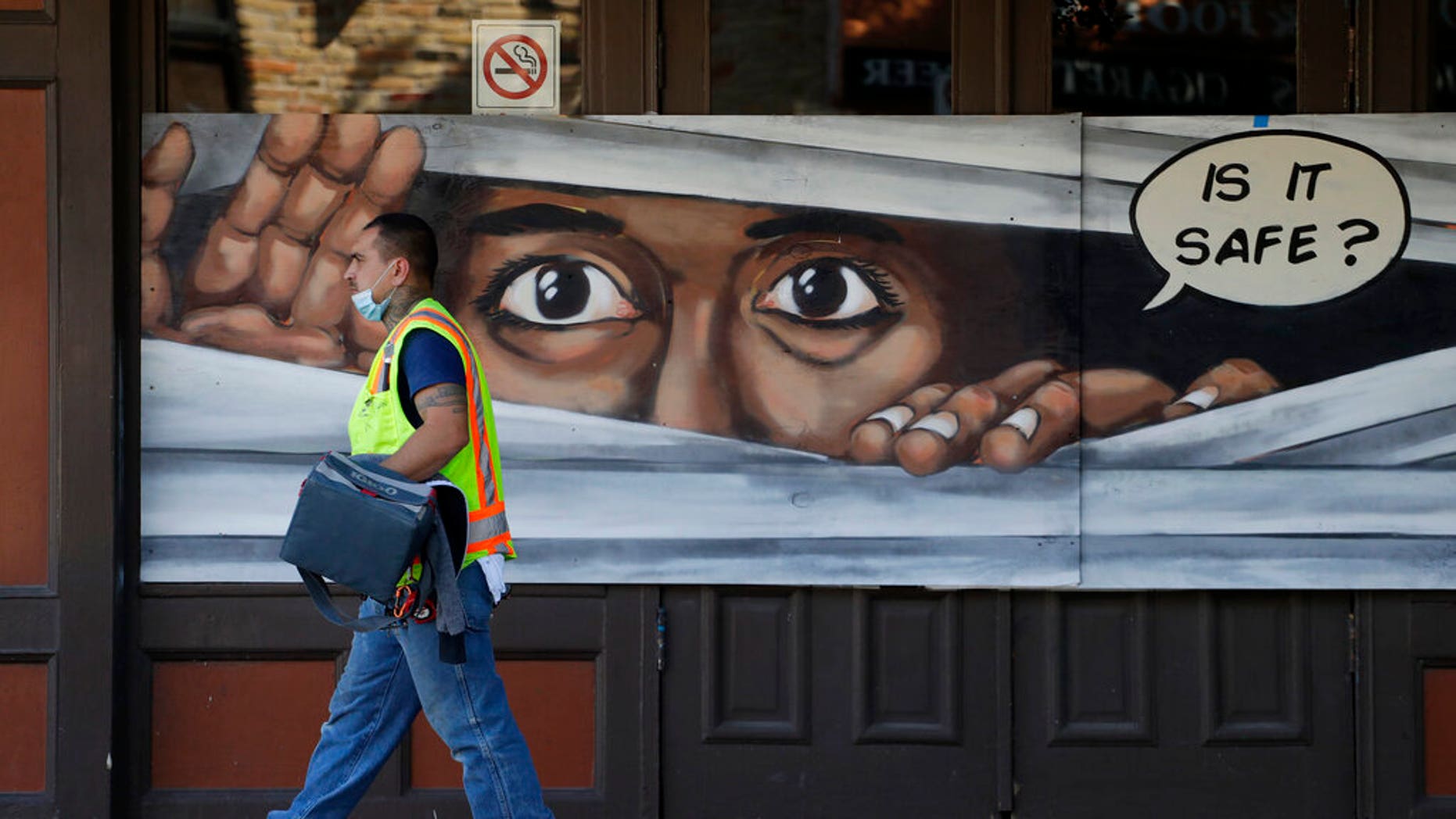 A construction worker walks past a mural painted on a boarded up business that is temporarily closed due to the COVID-19 pandemic, in Austin, Texas. Texas Gov. Greg Abbott announced he is relaxing some restrictions that have been imposed on some businesses. (AP Photo/Eric Gay)