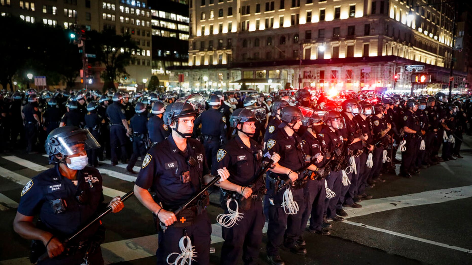 New York Police Department officers stand in formation after arresting multiple protesters marching after curfew on Fifth Avenue. (AP Photo/John Minchillo)