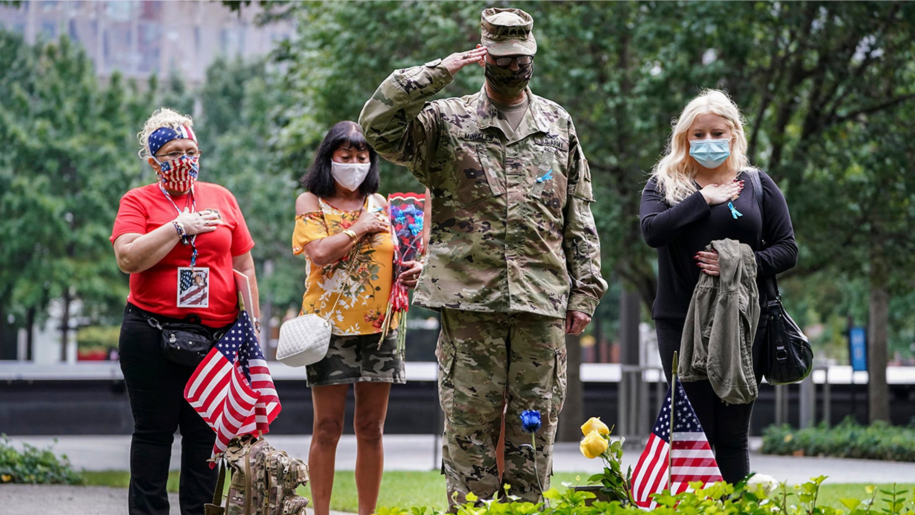 US Army Sgt. Edwin Morales, center right, salutes after places flowers for fallen FDNY firefighter Ruben D. Correa at the National September 11 Memorial and Museum, Friday, Sept. 11, 2020, in New York. (AP Photo/John Minchillo)