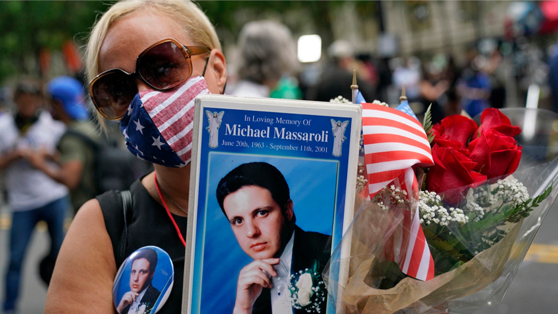 Diane Massaroli holds flowers, flags and a photo of her husband Michael Massaroli who died during the Sept. 11, 2001, attacks at the World Trade Center. (AP Photo/Mark Lennihan)