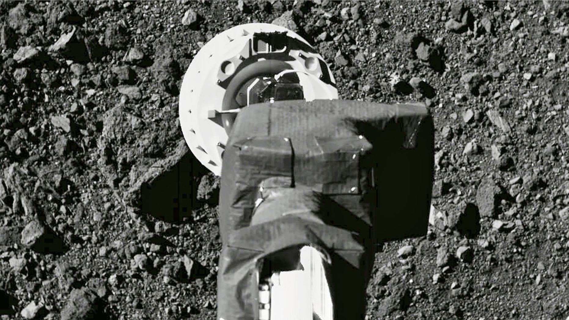 This Aug. 11, 2020 photo shows the sampling arm of the OSIRIS-REx spacecraft during a rehearsal for an approach to the "Nightingale" sample site on the surface of the asteroid Bennu. After almost two years circling the ancient asteroid, OSIRIS-REx will attempt to descend to the treacherous, boulder-packed surface and snatch a handful of rubble on Tuesday, Oct. 20, 2020. (NASA/Goddard/University of Arizona via AP)