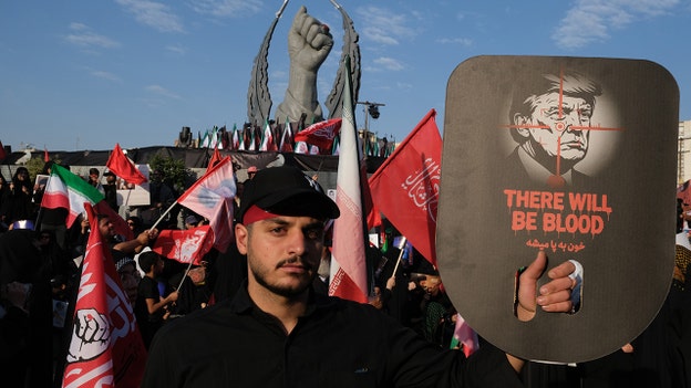 A mourner holds up an image of Donald Trump with a message of "There will be blood" on July 6, 2026 in Tehran, Iran. (Credit: Kaveh Kazemi/Getty Images)
