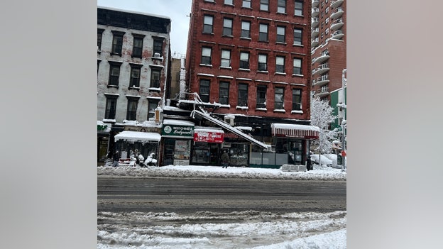 Dangling fire escape hangs over sidewalk as nor'easter hammers NYC