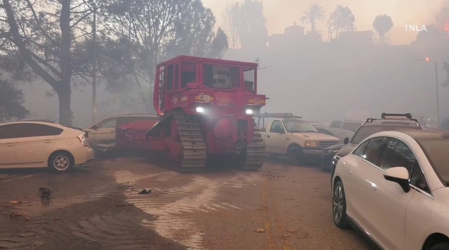 Bulldozers remove abandoned cars from road as fire burns in Southern California