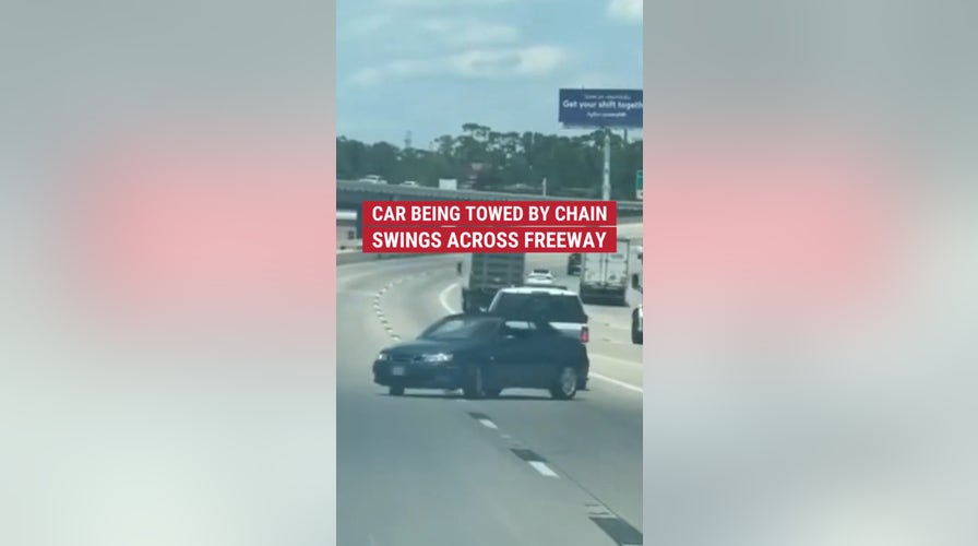 Wild moment caught on cam of a car being towed with only chain swerves out of control on a freeway