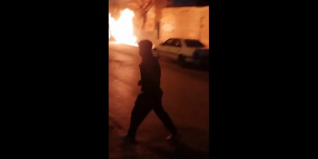 Iranian protesters chant as car overturned, fires burn outside police station