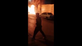 Iranian protesters chant as car overturned, fires burn outside police station