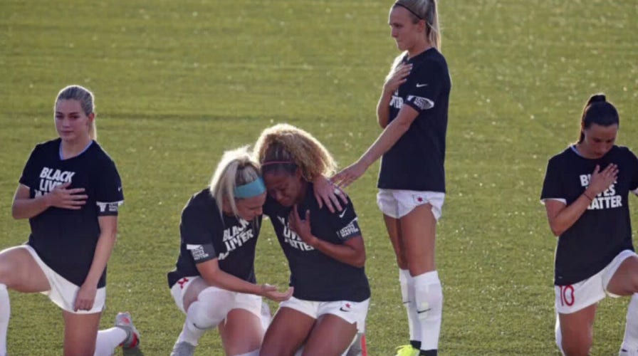 Women's soccer player stands for national anthem while teammates kneel