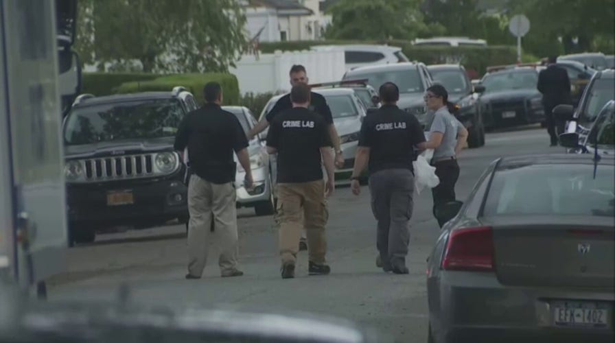 Police gather outside the home of the Gilgo Beach serial killer