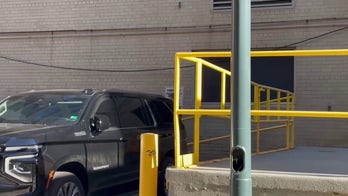 FBI agents load boxes into a car after searching John Bolton's DC office