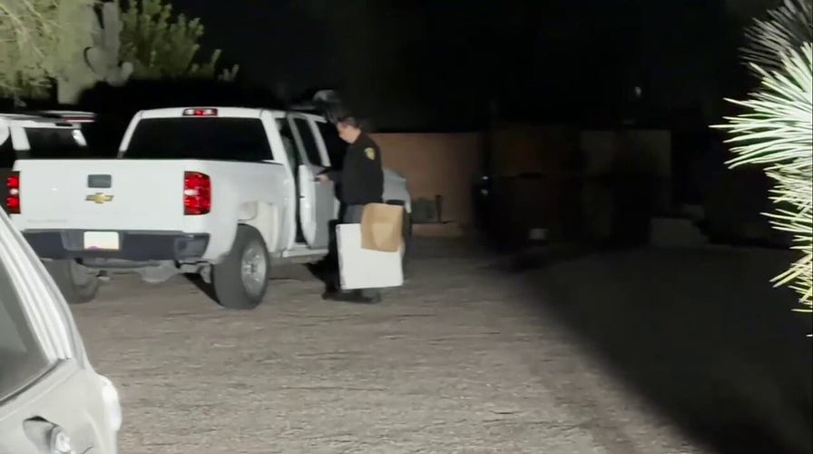 Officer seen leaving Annie Guthrie's location  with achromatic  lawsuit  and brownish  bag