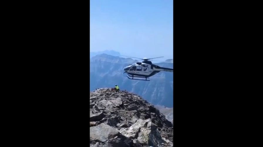 Helicopter makes daring approach to rugged peak during injured hiker rescue