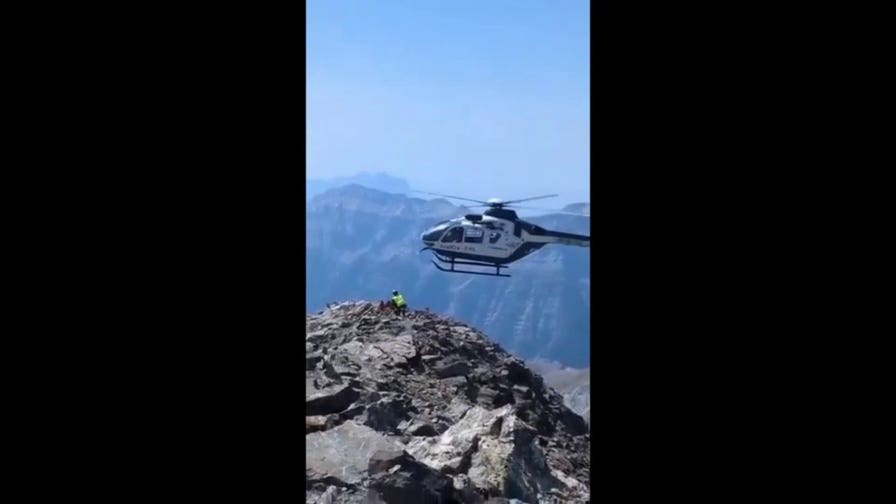 Helicopter makes daring approach to rugged peak during injured hiker rescue