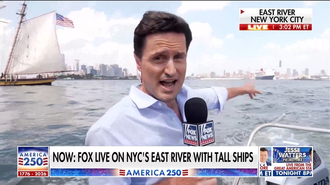 Tall ships sail past Statue of Liberty in New York Harbor