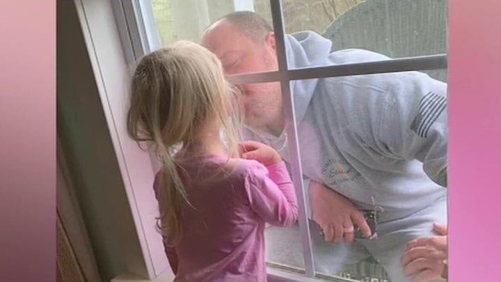 Quarantined firefighter kisses daughter through closed window