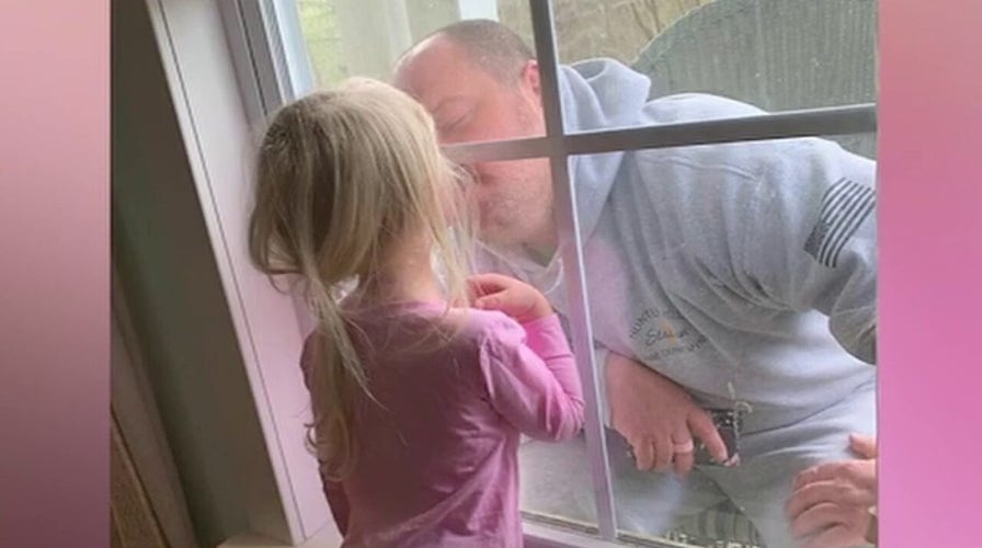 Quarantined firefighter kisses daughter through closed window