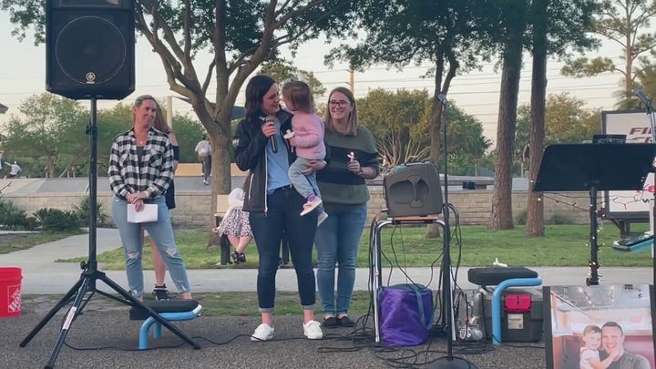 Kirsten Bridegan, holding her daughter Bexley, speaks at a vigil April 19 for her slain husband, Jared Bridegan