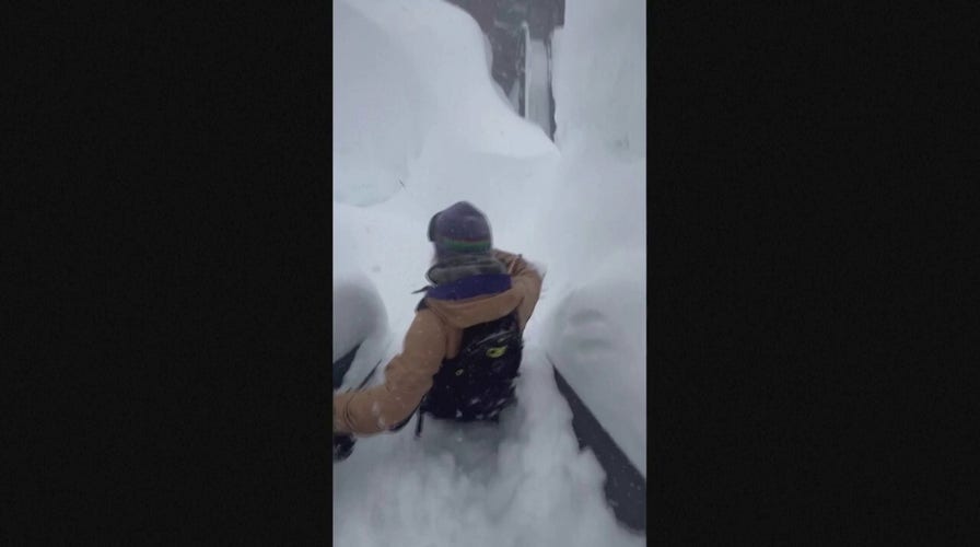 People in California wade through waist-deep snowdrifts.