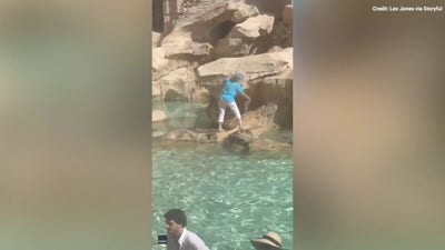 Woman wades through historic fountain to fill water bottle