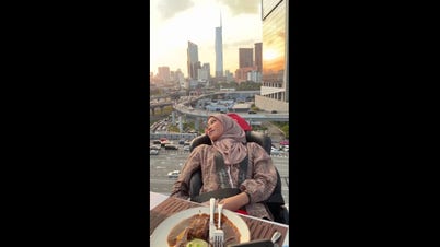 Thrill-seeker strapped in chair eats meal while hovering high above traffic
