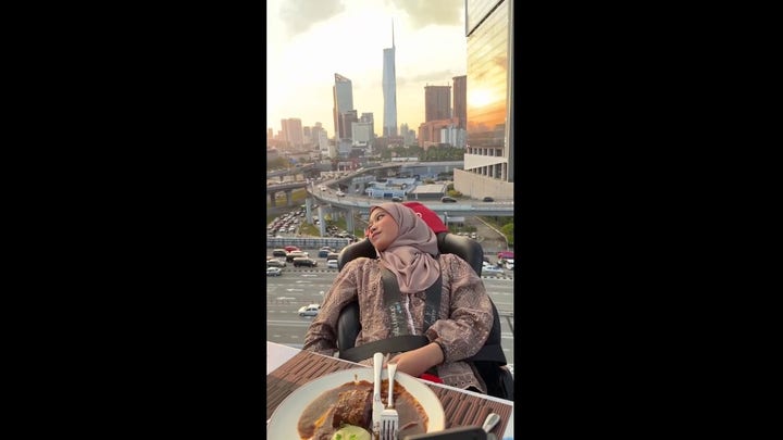 Thrill-seeker strapped in chair eats meal while hovering high above traffic