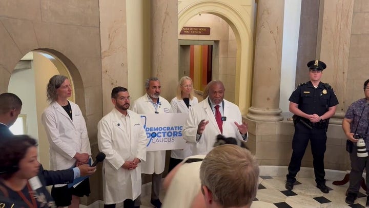 Tourists pass by Democratic Doctors Caucus press conference