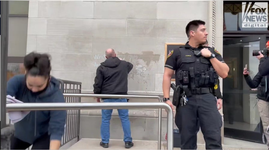 Officers stand guard as workers clear graffiti related to the Rittenhouse trial 