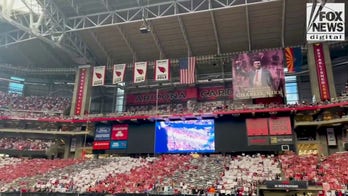 Crowd flashes posters in red, white and blue in moving tribute to Charlie Kirk