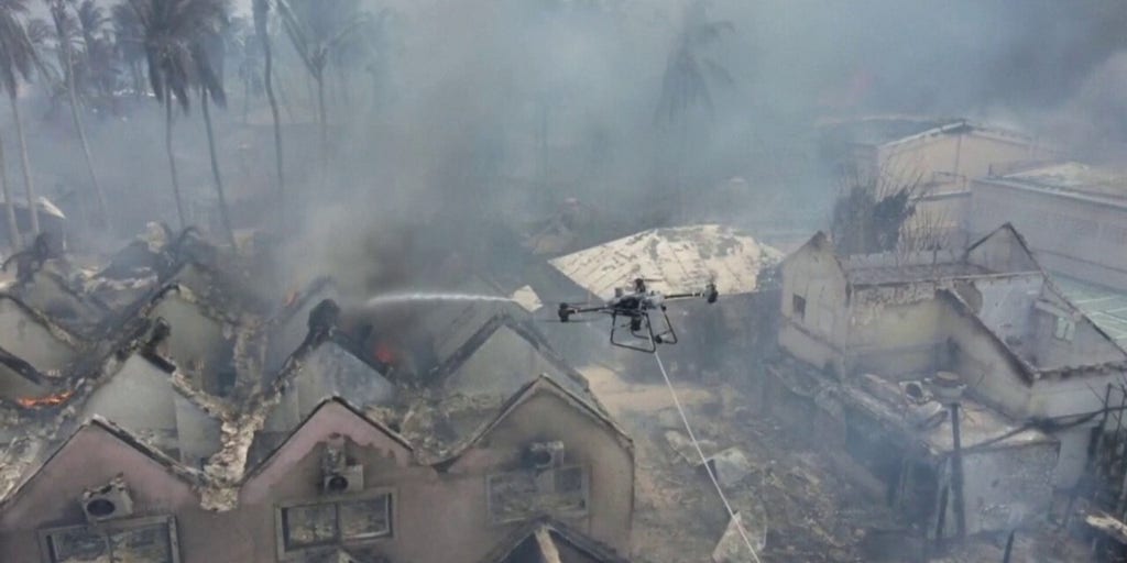 A drone sprays smoldering buildings with water after a fire blazed the Dominican resort town Bayahibe