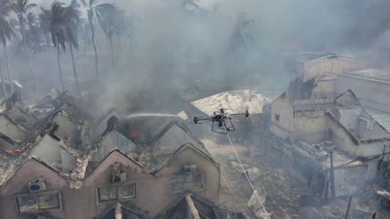 A drone sprays smoldering buildings with water after a fire blazed the Dominican resort town Bayahibe