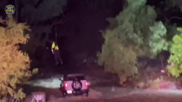 Nighttime water rescue of driver trapped in vehicle amidst rising floodwaters in Ojai area