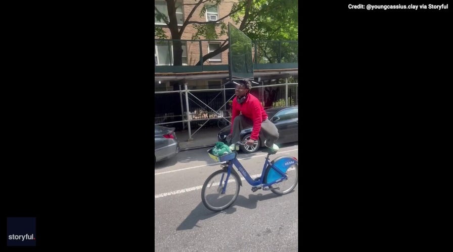 New York man balances TV on his head while riding bicycle — see the video!