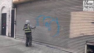 Man paints over graffiti on vandalized garage door in downtown Los Angeles