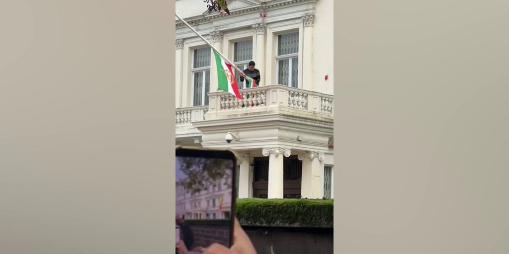 Protester at Iran's embassy in London installs pre-revolution flag after tearing down Islamic regime's symbol