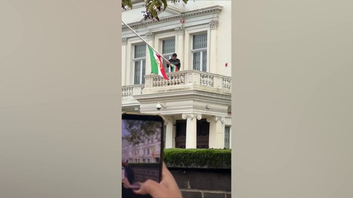 Protester at Iran's embassy in London installs pre-revolution flag after tearing down the Islamic regime's symbol