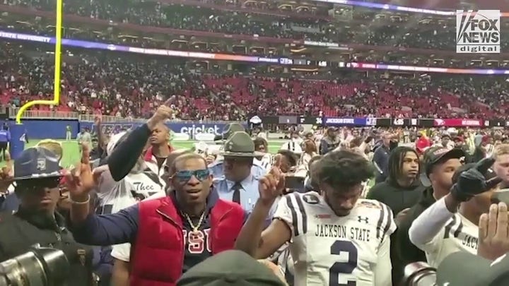 Coach Deion Sanders on the field with Jackson State players at Mercedes-Benz Stadium