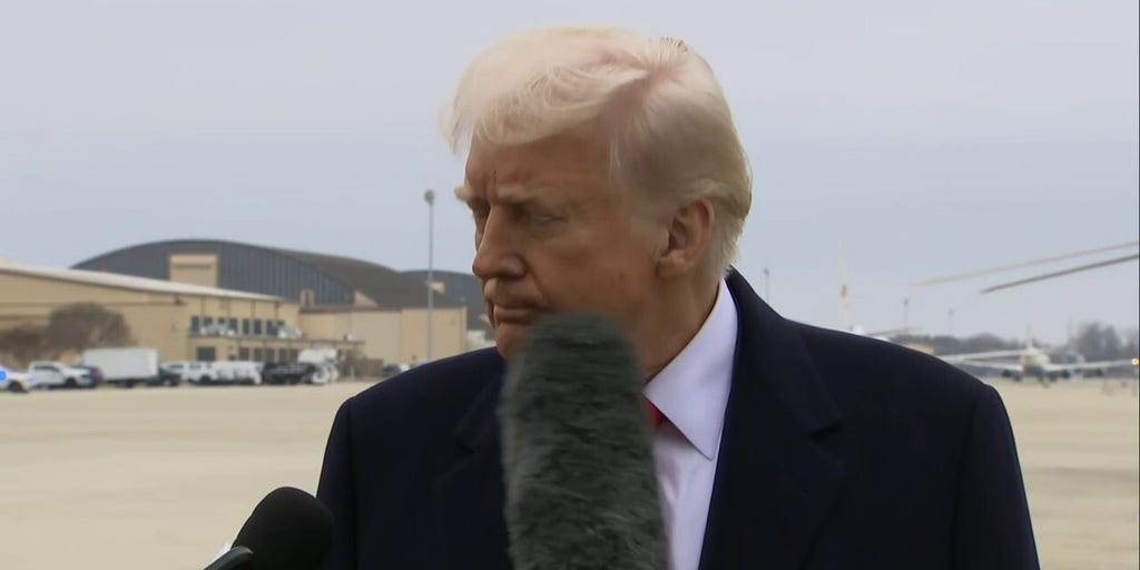 President Donald Trump is hit by a reporter's microphone while speaking with media at Joint Base Andrews