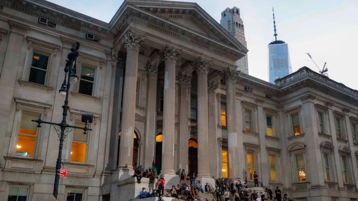 Protesters remain outside New York City Hall after city council votes to cut $1B from NYPD budget