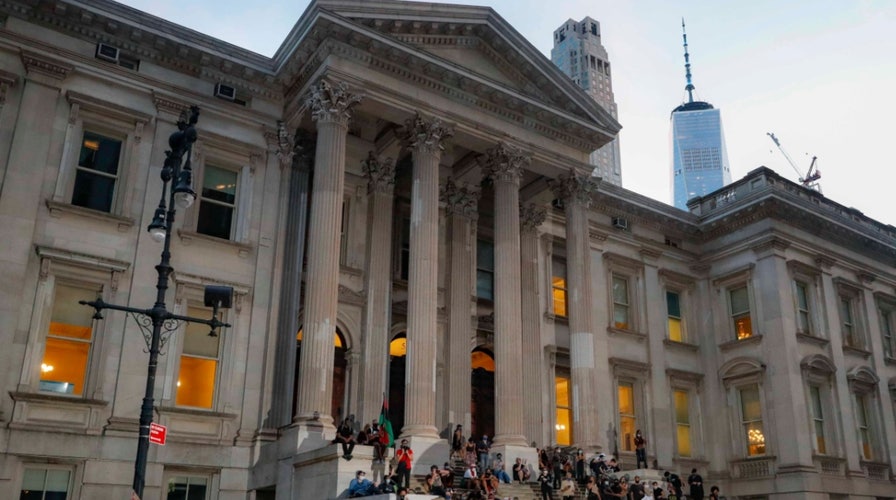 Protesters remain outside New York City Hall after city council votes to cut $1B from NYPD budget